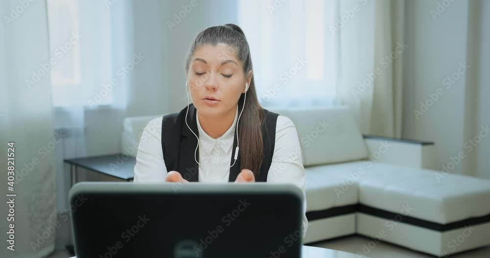 Concentrated student with long hair in ponytail looks into black computer display and talks at online lecture staying home Concentrated student with long hair in ponytail looks into black computer display and talks at online lecture staying home