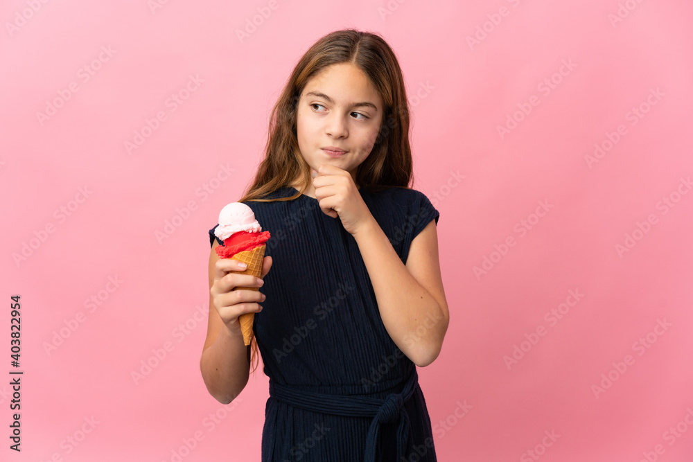 Child with a cornet ice cream over isolated pink background and looking up Child with a cornet ice cream over isolated pink background and looking up