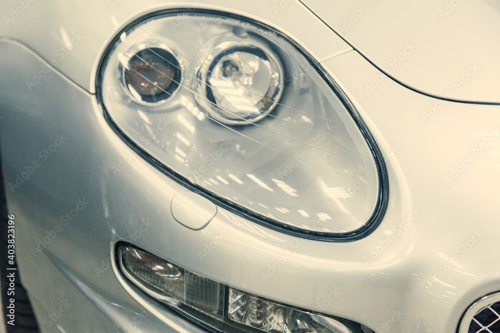 close-up halogen headlight of white retro car. car in the garage