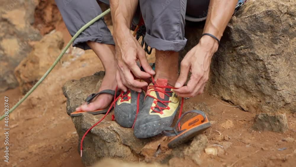 Man putting on his rock climbing shoes preparing to rock climbing Man putting on his rock climbing shoes preparing to rock climbing