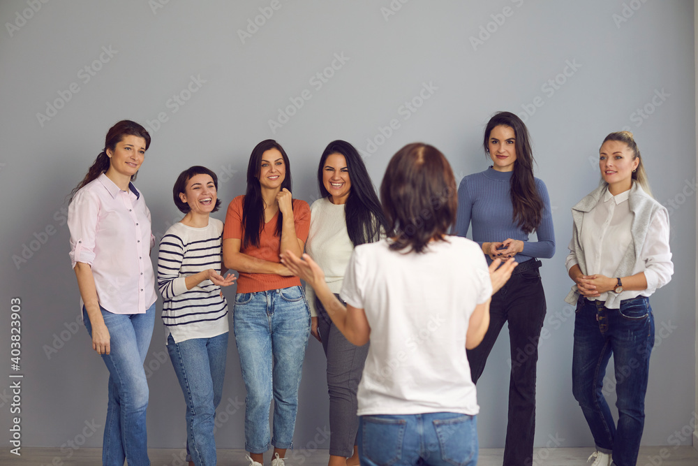Professional life coach meeting with young female audience, giving a talk and telling a story. Group of happy smiling women in their 20s and 30s listening to motivational advice by interesting speaker Professional life coach meeting with young female audience, giving a talk and telling a story. Group of happy smiling women in their 20s and 30s listening to motivational advice by interesting speaker