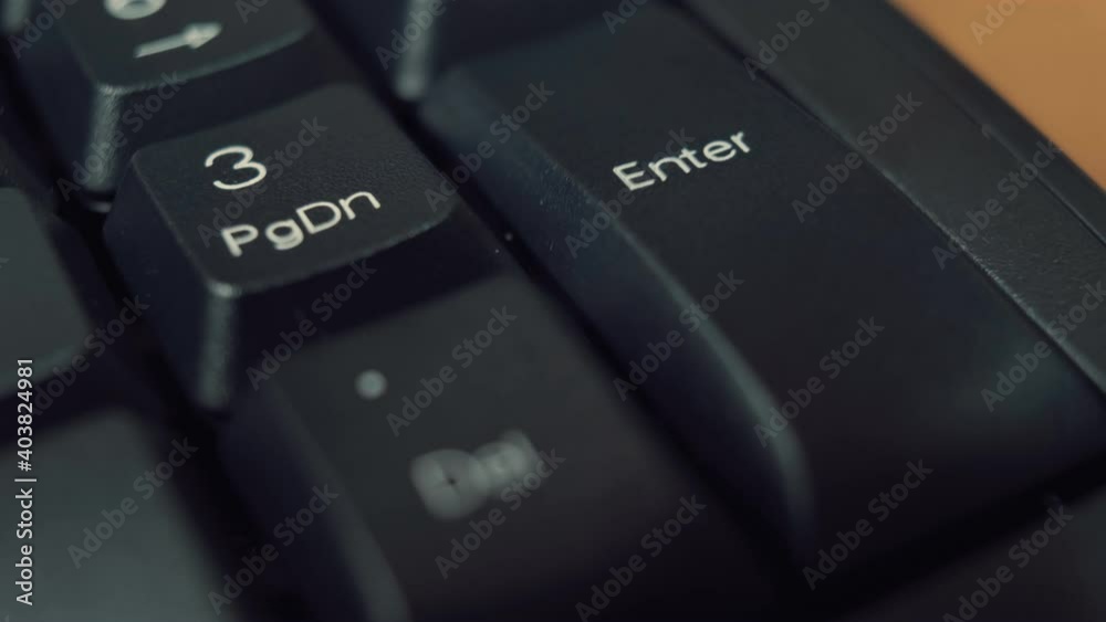 Person finger repeatedly pressing the enter key on a black keyboard. Macro shot.