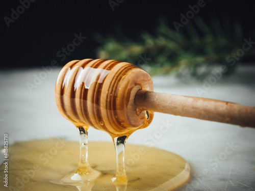 Honey wood dipper is pouring honey. Honey dripping on white marble top. Healthy sweet ingredient for breakfast and pastry. Golden, yellow, raw honey.