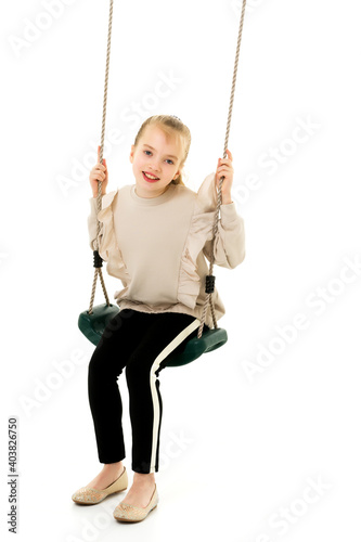 Happy little girl schoolgirl swinging on a swing.