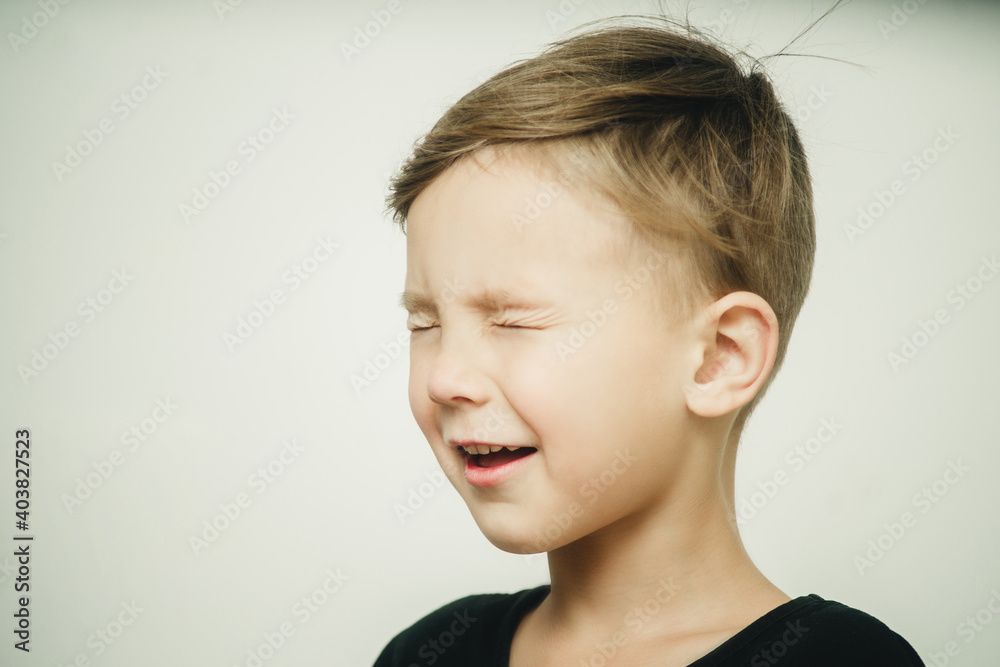portrait of a surprised and cheerful boy with closed eyes on a white background portrait of a surprised and cheerful boy with closed eyes on a white background