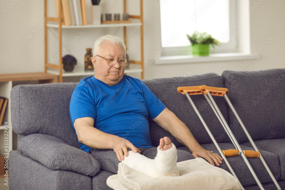 © Studio Romantic - Rehabilitation after domestic or car accident injury: Senior male stays at home, waiting for bone fracture to heal. Old man with broken leg in plaster cast sitting on sofa with crutches in living-room © Studio Romantic - Rehabilitation after domestic or car accident injury: Senior male stays at home, waiting for bone fracture to heal. Old man with broken leg in plaster cast sitting on sofa with crutches in living-room