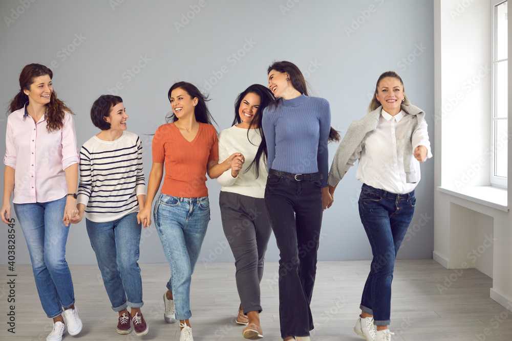 Obraz premium Always ready to support each other. Group of happy confident smiling young women in their 20s and 30s walking together and holding hands. Concept of success, female solidarity and mutual understanding