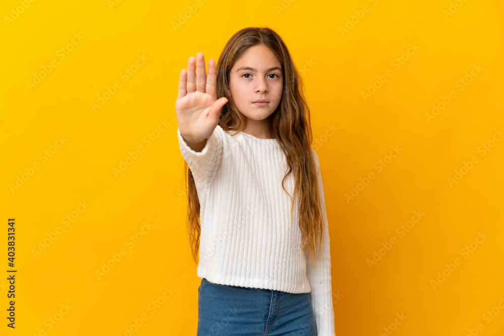 Child over isolated yellow background making stop gesture Child over isolated yellow background making stop gesture
