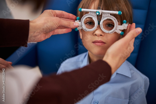 Adult putting a trial frame on kid eyes