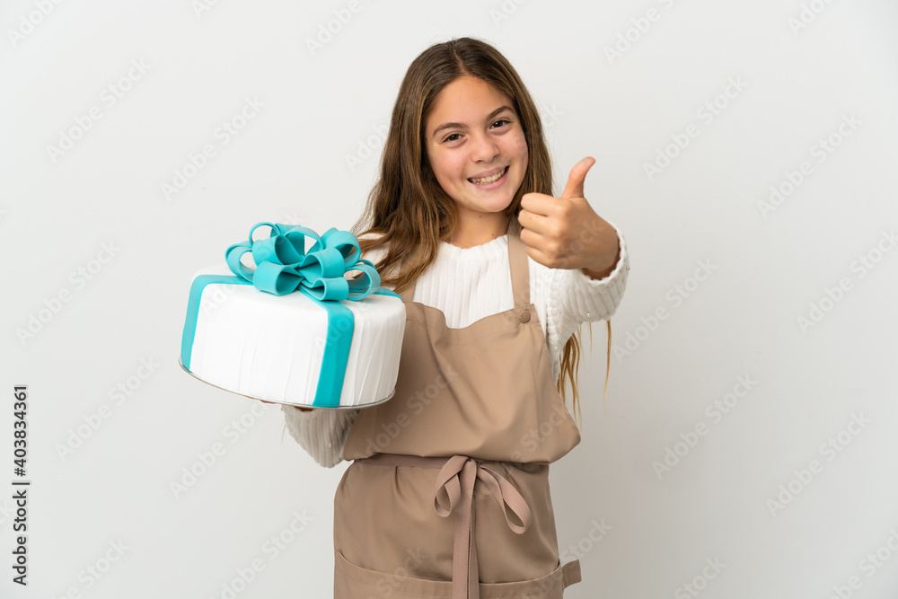 Little girl holding a big cake over isolated white background with thumbs up because something good has happened