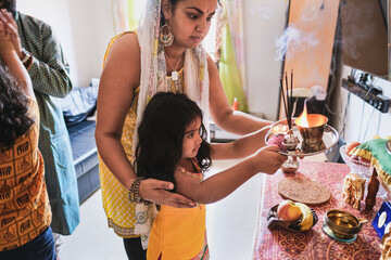 Indian family celebrate hindu event together at home - Traditional dress and religious celebration - Parents and children love