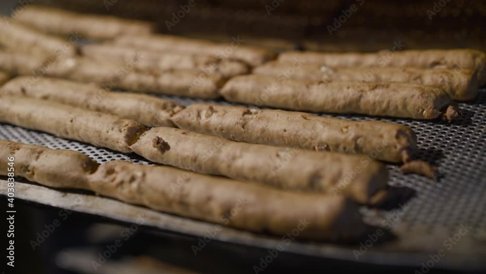 View of process of baking bread sticks on plates in professional oven in bakery View of process of baking bread sticks on plates in professional oven in bakery
