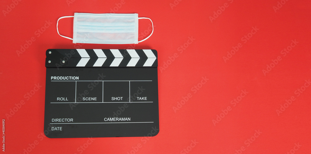 Black Clapper board or movie slate with face mask. it use in video production,movies and cinema industry on red background..