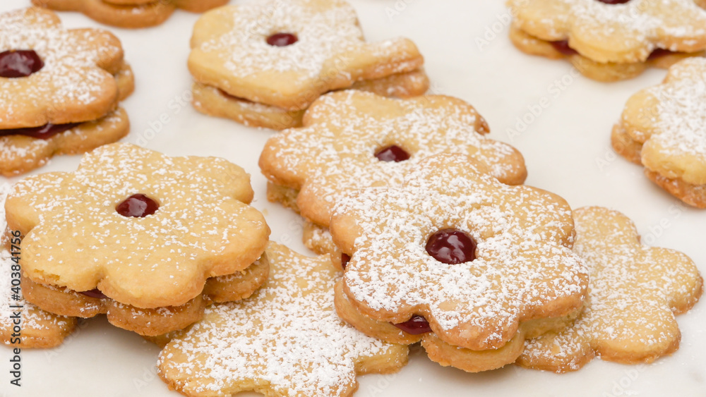 Flower shaped shortbread cookies filled with raspberry jam. Fresh baked cookies close up on white background