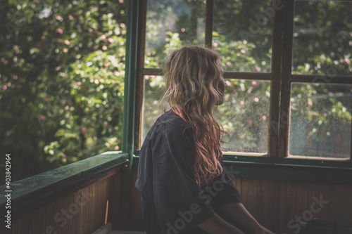 cute teenage child with long blond hair behind the window alone