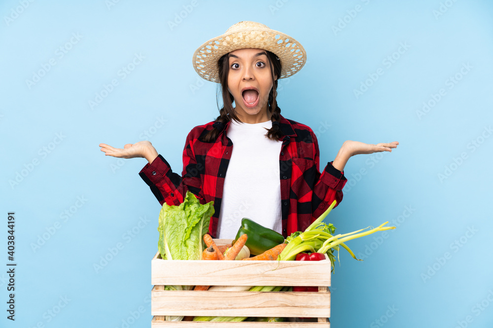 Young farmer Woman holding fresh vegetables in a wooden basket with shocked facial expression