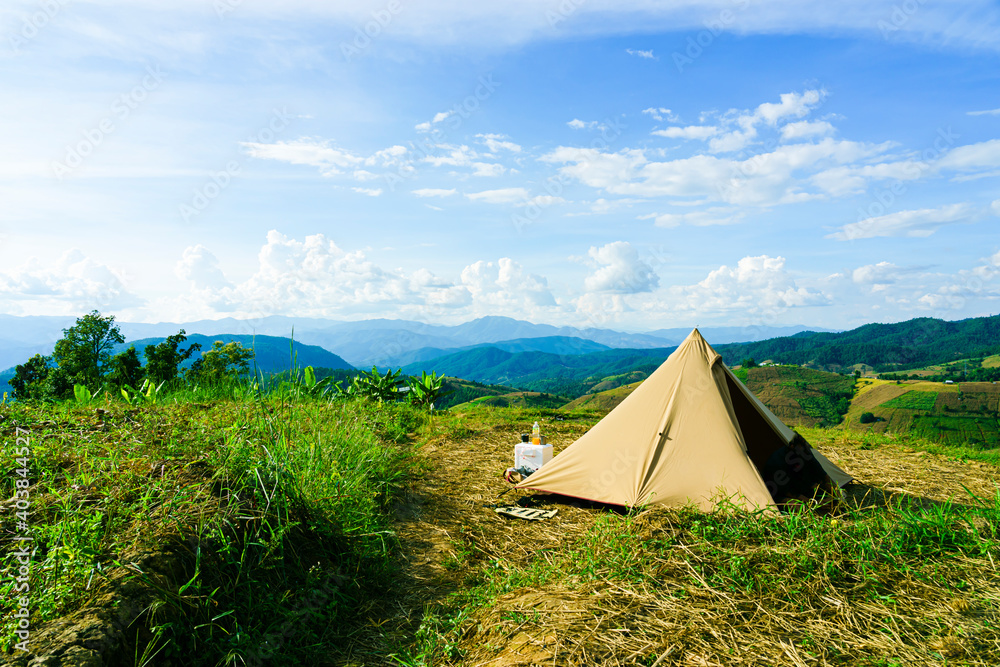 Tourist tent camping on the hill beneath the mountains under dramatic sky and golden terrace fields view in Chiangmai , northern of Thailand.