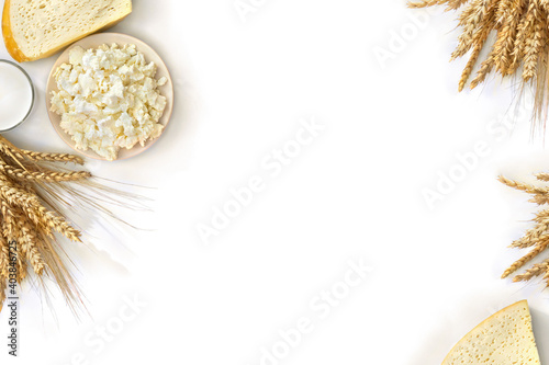 Frame of cheese, barley and wheat and milk in glass on a white background with space for text. Top view, flat lay