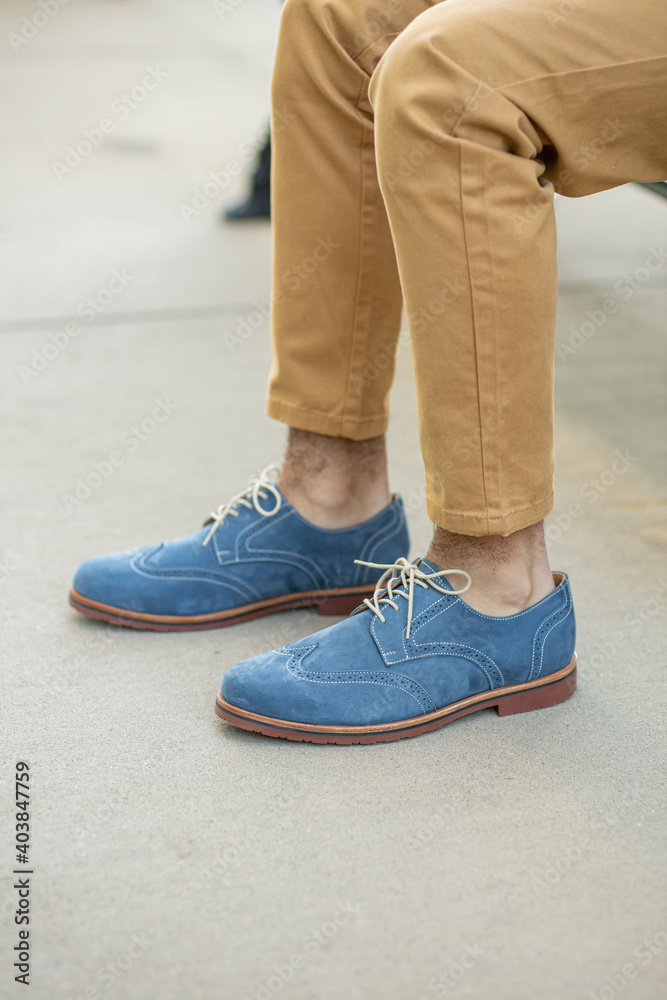 A pair of colorful blue navy formal mens shoes with wingtip fashion, dress with Khakis.