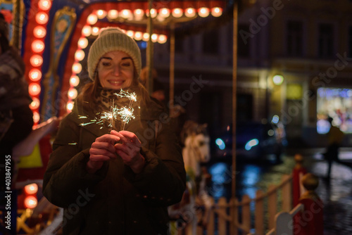 Smiling woman with sparklers on Christmas market in Tallinn