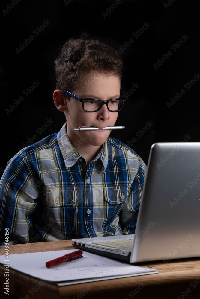 Student on laptop at home with pen Student on laptop at home with pen