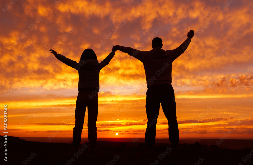Fototapeta premium A loving couple on the background of a fiery orange sunset.