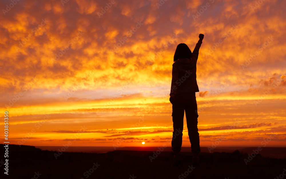 Woman hiker with hands up arms during sunset. Silhouette of an unrecognizable girl.