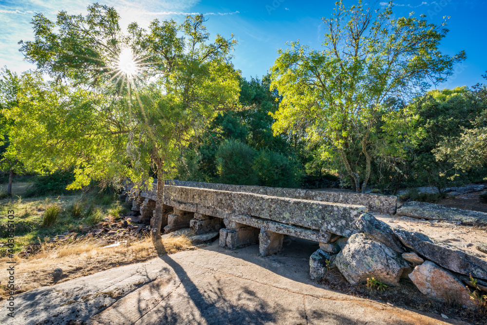 Antique stone bridge over dry river with sunstar