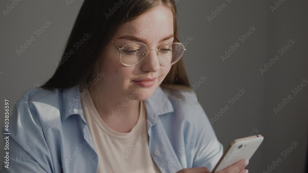 Chubby teenage girl in eyeglasses typing on smartphone, chatting social networks Chubby teenage girl in eyeglasses typing on smartphone, chatting social networks