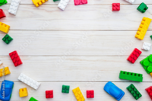 Top view of colorful plastic toy bricks on a white wooden background. Baby kids toys background