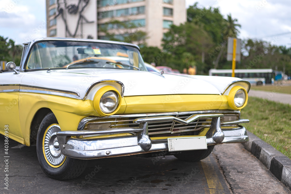 front view of a yellow and white vintage car on the streets of havana cuba