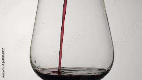 Red wine is poured into a wine glass. White background