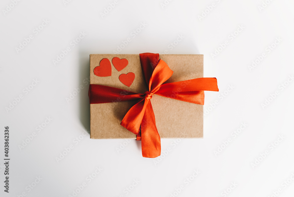 Gift box with red ribbon and hearts on the white table. Valentine's day surprise concept