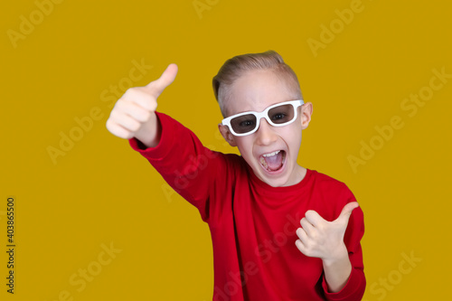 a cheerful child in red clothes and glasses shows a thumbs up on a yellow background