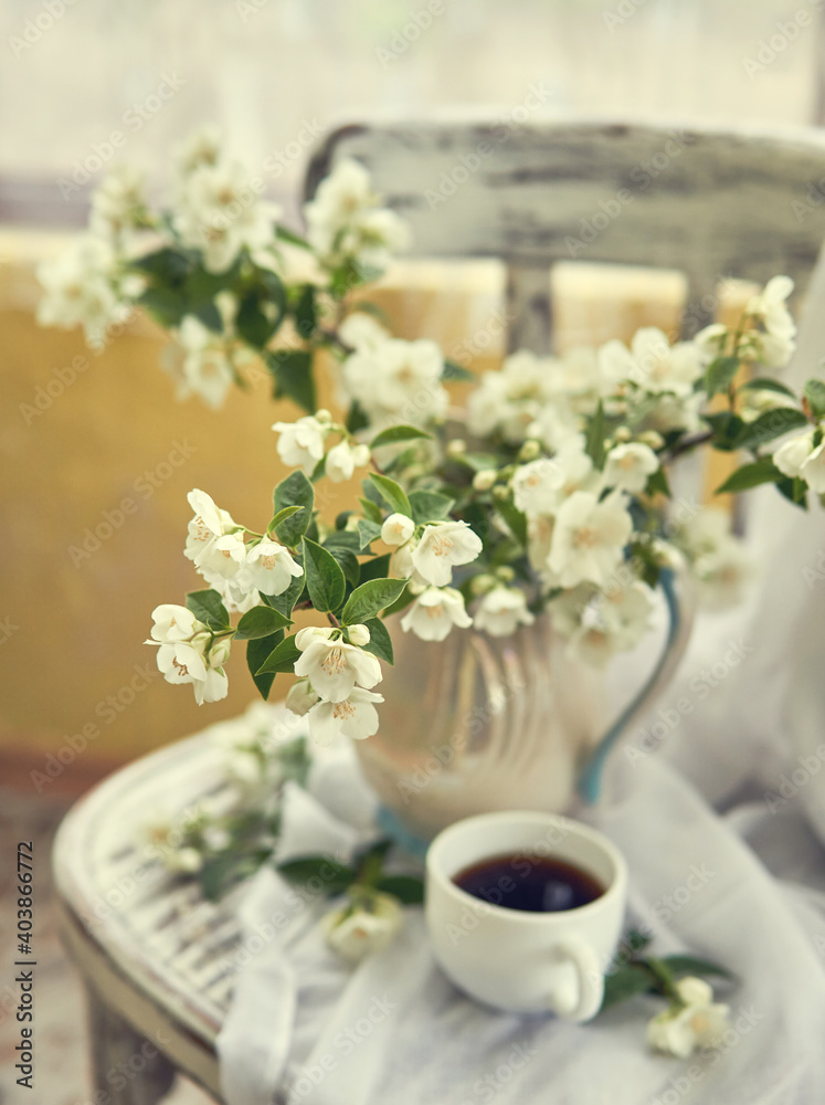 Jasmine flowers in a white vase. Stillife with jasmine and cup of coffee. Jasmine flowers in a white vase. Stillife with jasmine and cup of coffee.