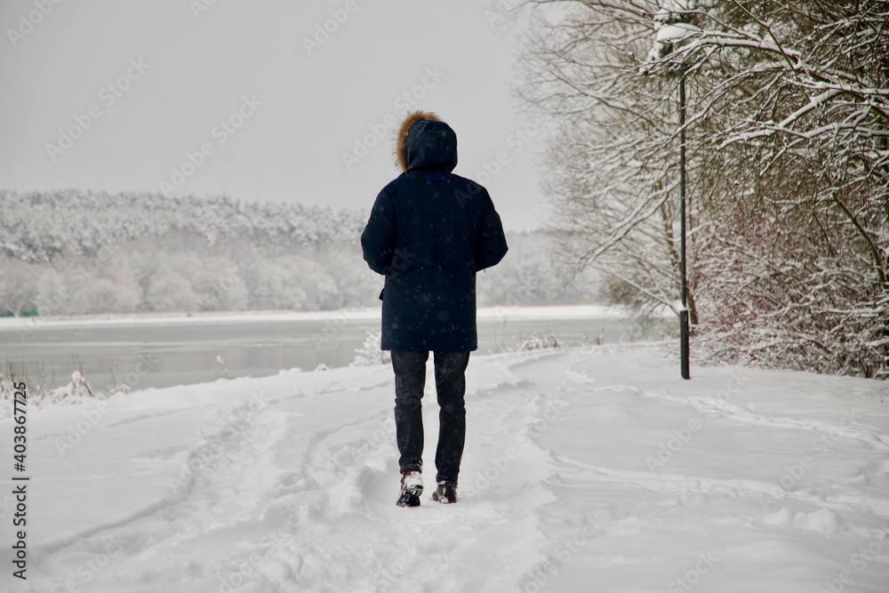 Person walk on the way to the winter white lake in the park.
