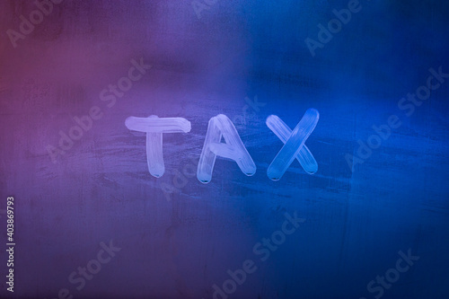 word tax hadwritten on night wet window glass surface photo