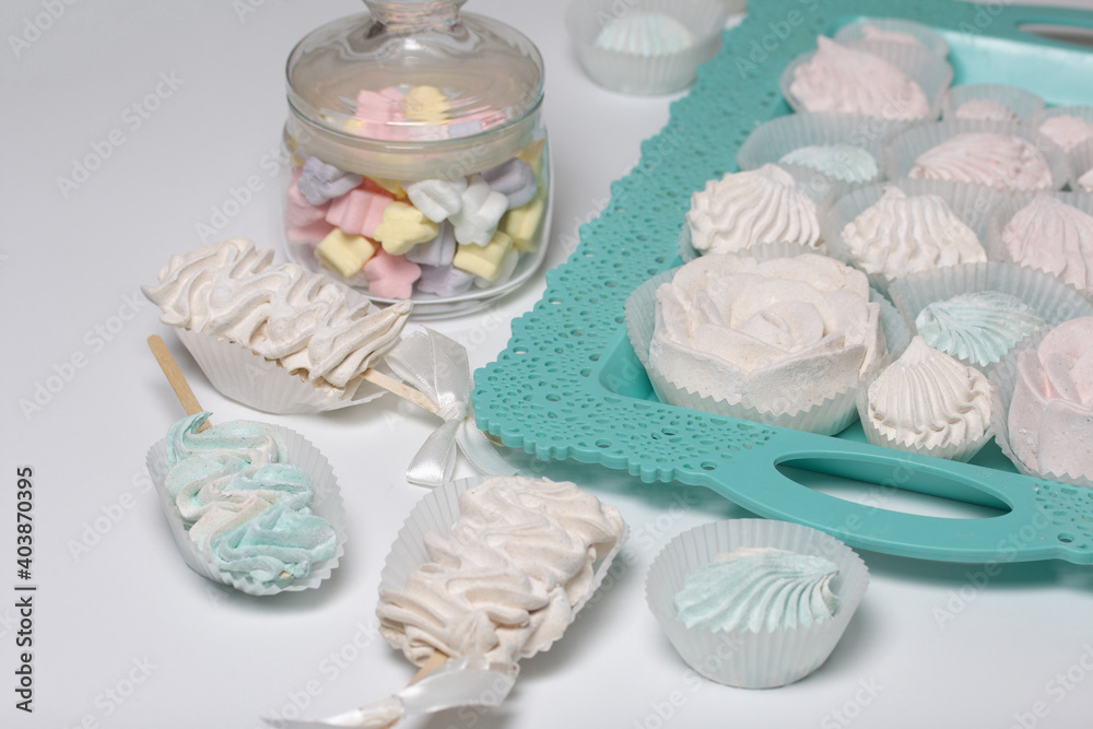 Zephyr on a stick. Nearby are marshmallows in a jar and on a tray. Various shapes and shades. Close-up shot. Zephyr on a stick. Nearby are marshmallows in a jar and on a tray. Various shapes and shades. Close-up shot.