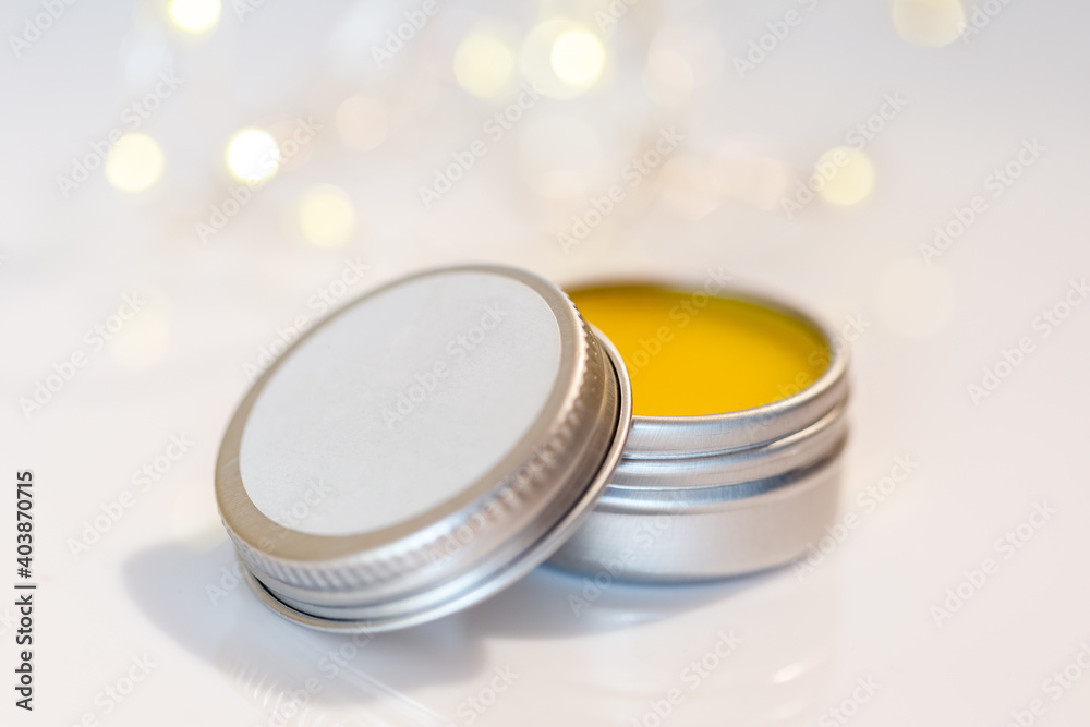 Lip balm in metal jar over light bokeh background Lip balm in metal jar over light bokeh background