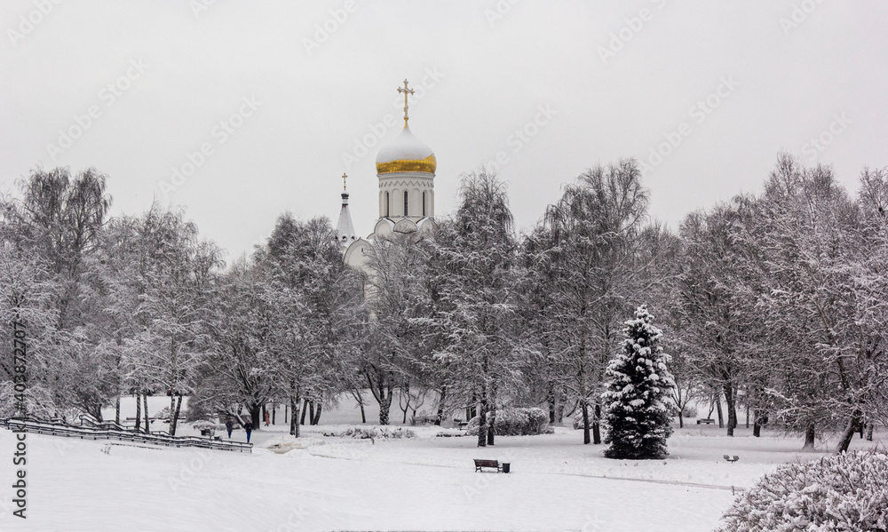 Winter landscape in a city park with a church in the background.