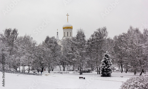 Winter landscape in a city park with a church in the background. © Sviatlana