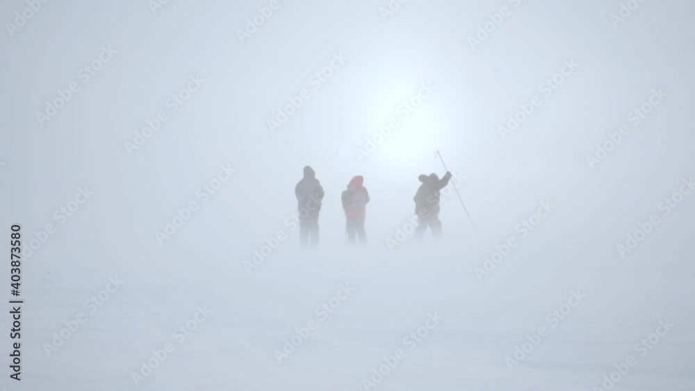 three people in a snowstorm on the background of the sun
