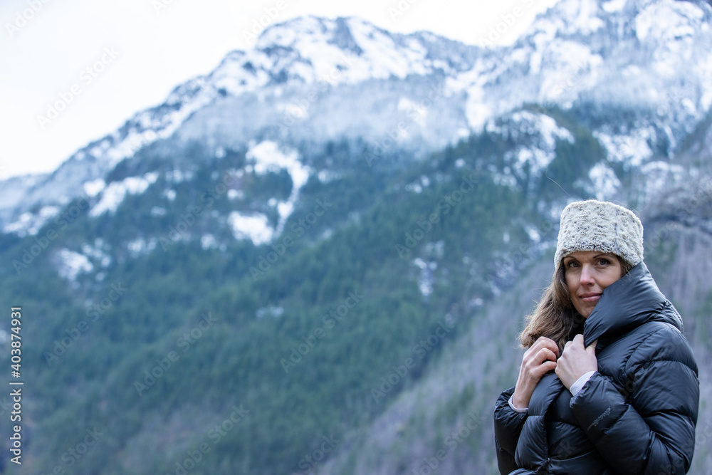 A woman outside in nature takes in the view of beautiful, snow covered mountains