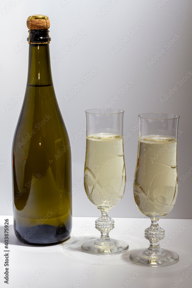 Green bottle with champagne inside and two glasses with champagne on a white background. Green bottle with champagne inside and two glasses with champagne on a white background.