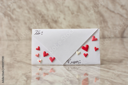 Letter envelope on table decorated with hearts. Message for Valentine's Day. 