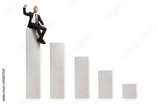 Professional man sitting on the highest column of a bar chart and gesturing a win sign