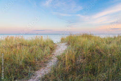 sand path trough the dunes towards the ocean under the beautiful sunset sky