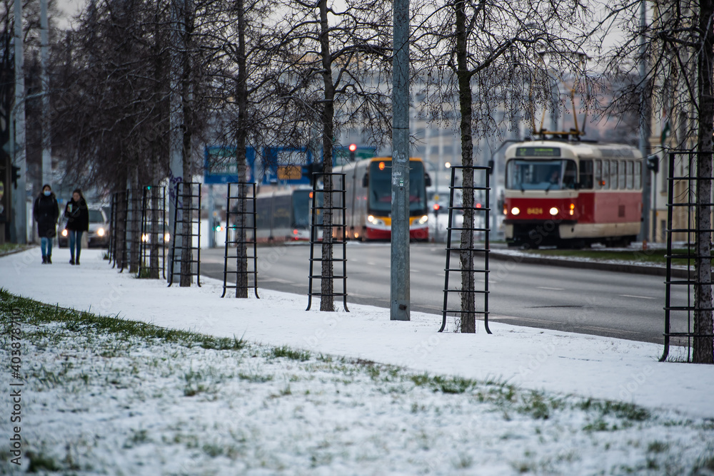 Naklejka premium Snowing day on Prague. People walk on Park Letna while tram travel through the city, close to Hradcanska in Prague 6