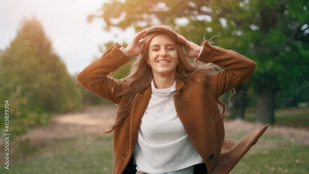The happy young woman is dancing and jumping in the forest. The pretty girl is running and smiling to the camera. Autumn sunset at a background. The happy young woman is dancing and jumping in the forest. The pretty girl is running and smiling to the camera. Autumn sunset at a background.