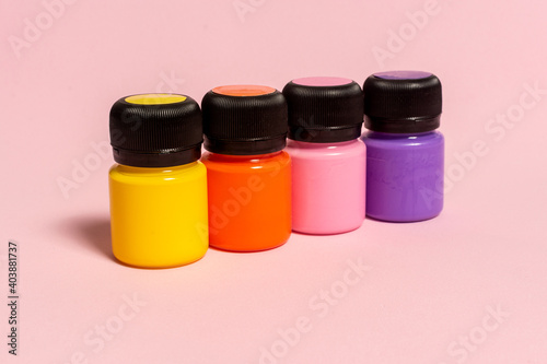 cans of acrylic paints of different colors on pink background